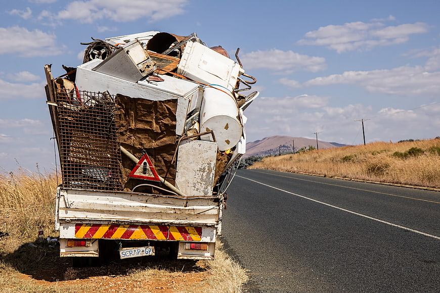 Overloaded scrap metal truck parked on rural road