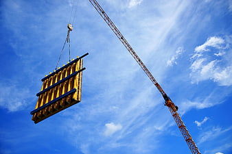 Yellow Construction Formwork Suspended by Crane Against Blue Sky