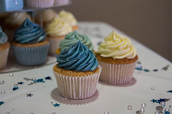 Pastel Blue and Yellow Frosted Cupcakes on White Table