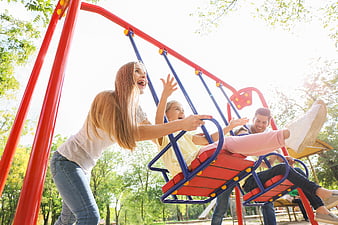 Happy family playing on swings in sunny park