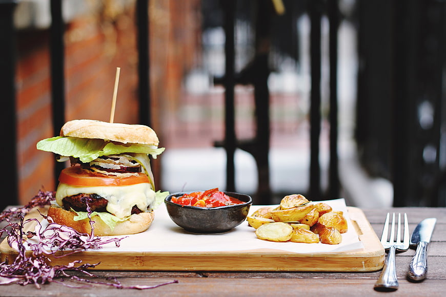 Gourmet Burger with Roasted Potatoes and Salad on Wooden Board