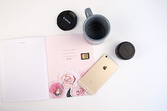 Flat lay of workspace with notebook, smartphone, and camera lens caps