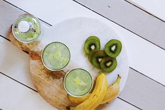 Top view of kiwi banana smoothie with fresh fruit on white wood