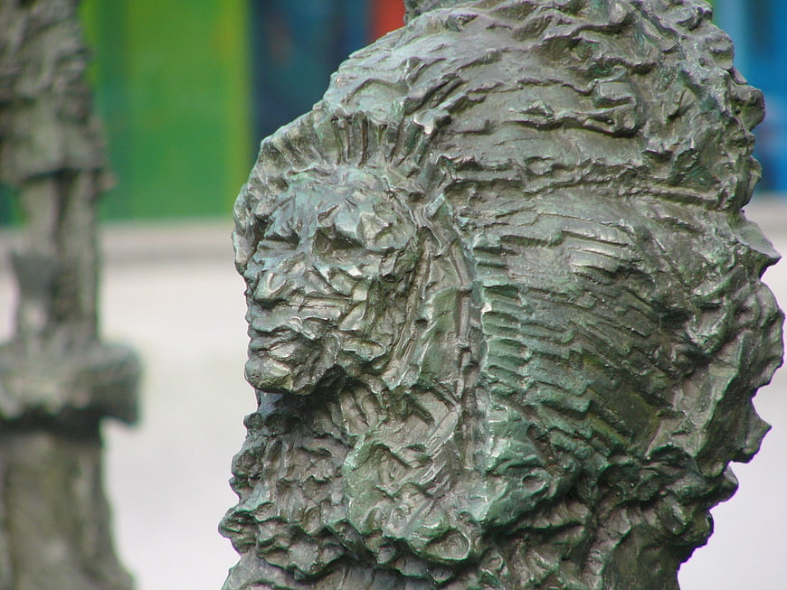 Close-up of textured bronze sculpture head with green patina