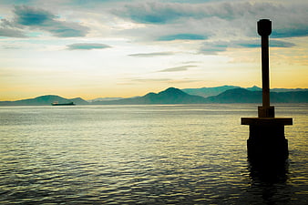 Serene Ocean Sunset with Distant Mountains and Ship