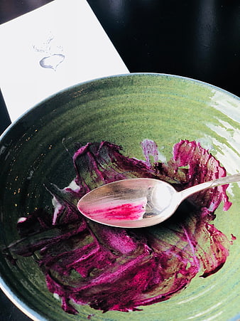 Empty green ceramic bowl with beetroot residue and spoon