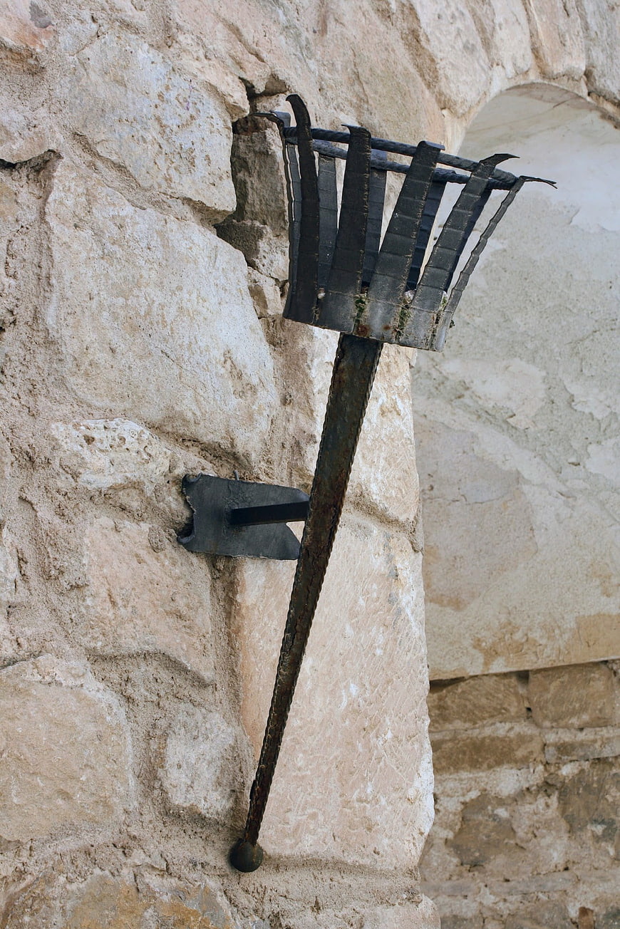 Rusty wrought iron lantern on ancient stone wall