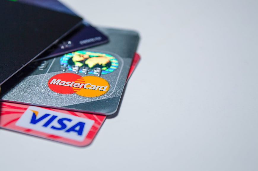 Stack of credit cards with Visa and Mastercard logos on white background