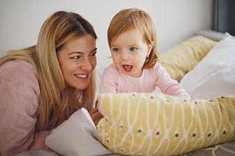 Happy Mother and Toddler Playing on Bed