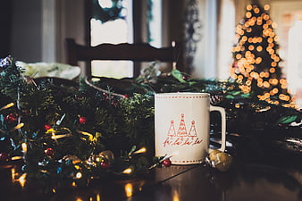 Festive Christmas Mug on Table with Garland and Bokeh Lights