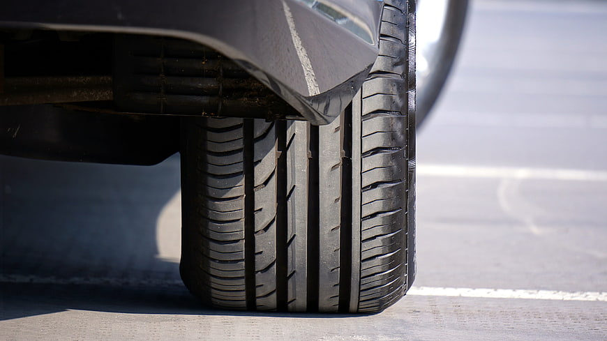 Close-up of car tire tread on asphalt parking lot