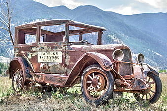 Rusty vintage Model T truck in mountain field