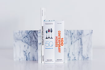 White books held by marble bookends on a white surface