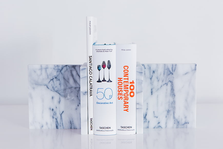 White books held by marble bookends on a white surface
