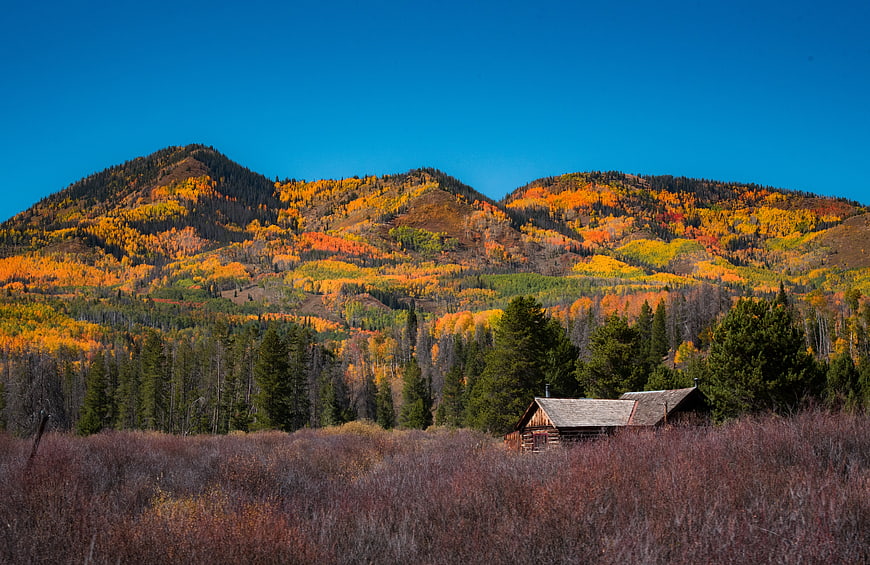 Rustic Cabin in Autumn Mountain Landscape with Golden Aspen Trees