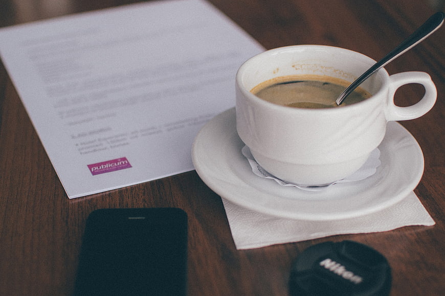 Coffee cup, smartphone, and document on wooden desk