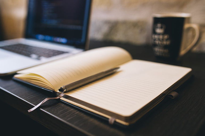 Open Notebook, Pen, and Laptop on Dark Desk