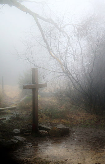 Misty wooden cross on a foggy forest path