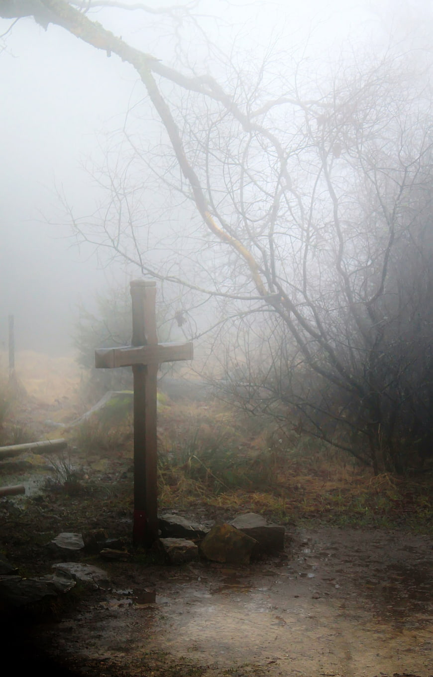 Misty wooden cross on a foggy forest path
