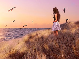 Woman in Floral Dress Standing on Dune at Sunset