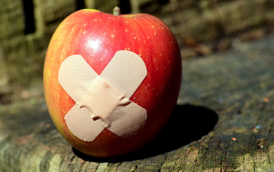Red apple with adhesive bandage on rustic wooden surface