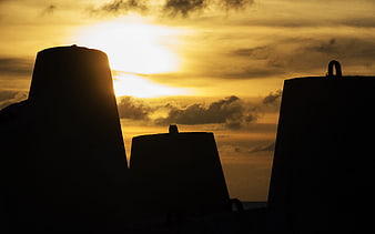 Silhouetted concrete structures against a golden sunset sky