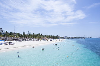Wide view of turquoise Caribbean beach with swimmers and white sand