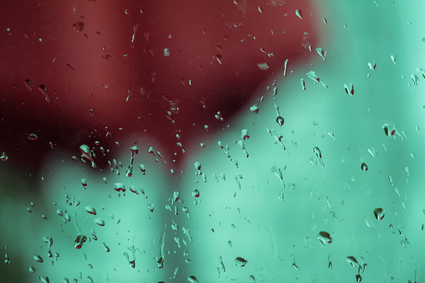 Raindrops on Glass with Red and Teal Bokeh Background
