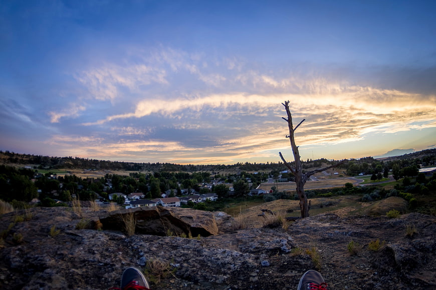 Hiking shoes overlooking suburban valley at sunset