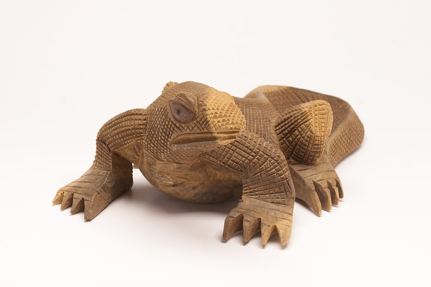Hand-carved wooden lizard sculpture on white background
