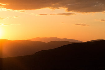 Golden Sunset Over Layered Mountain Silhouettes