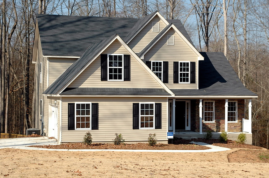 New suburban house exterior with beige siding and brick porch