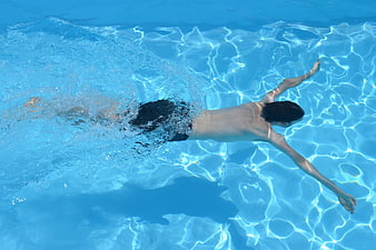 Woman swimming butterfly stroke in a bright blue pool