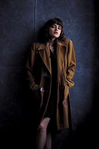 Woman in Brown Trench Coat Against Dark Textured Wall