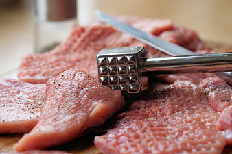 Raw pork cutlets with meat tenderizer and knife on wooden board