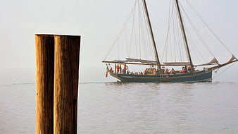 Wooden Mooring Post with Sailboat on Calm Water