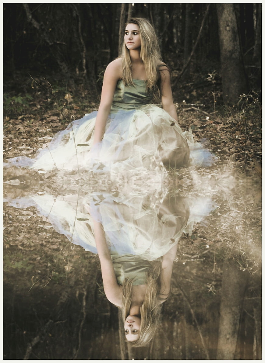 Young woman in formal dress with reflection in forest