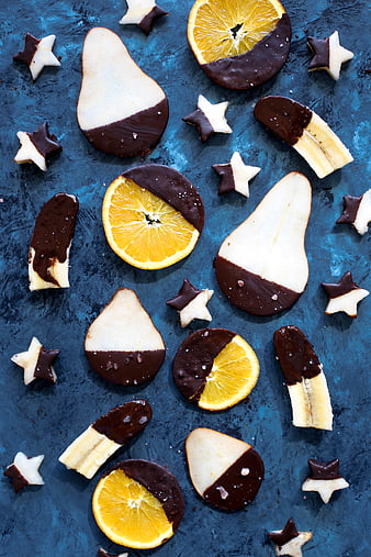 Flat lay of chocolate dipped fruit slices on blue background