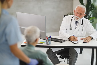 Senior doctor consulting with elderly patient in clinic