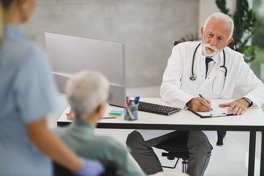 Senior doctor consulting with elderly patient in clinic