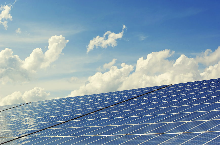 Blue Solar Panels Against Blue Sky with White Clouds