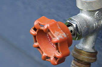 Close-up of red industrial valve handle on metal pipe
