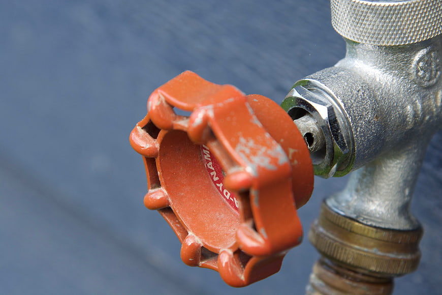 Close-up of red industrial valve handle on metal pipe