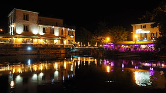 Nighttime river scene with illuminated restaurants and reflections