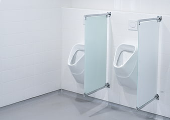 Modern white urinals with glass dividers in a clean public restroom