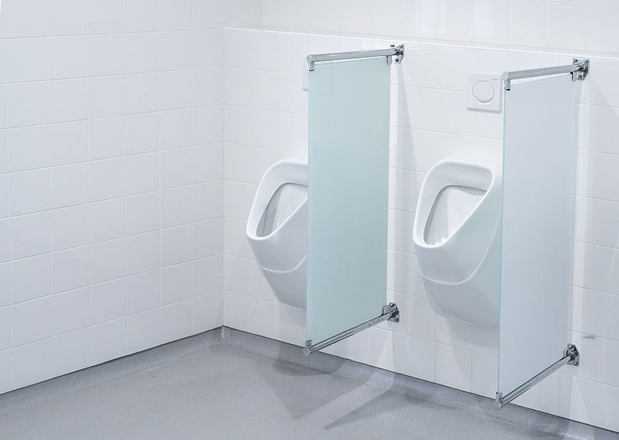 Modern white urinals with glass dividers in a clean public restroom
