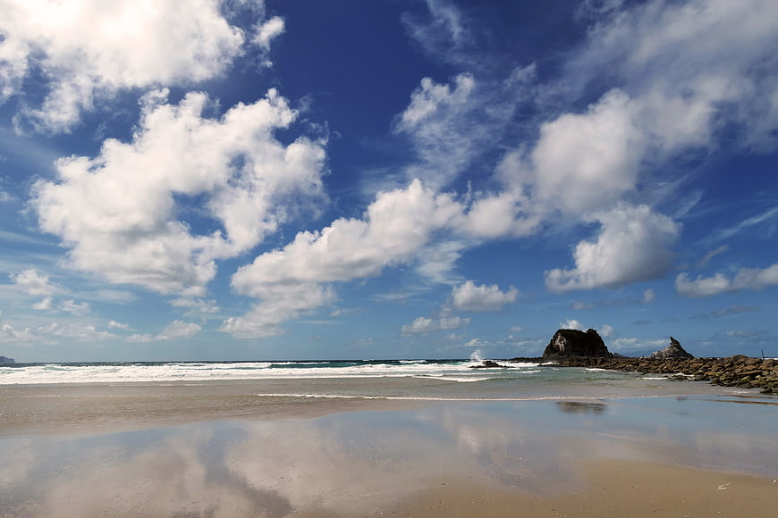 Serene Beach Landscape with Cloud Reflections on Wet Sand
