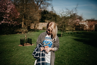 Blonde woman in park holding plaid shirt