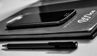 Black and white smartphone on office notebook with pen