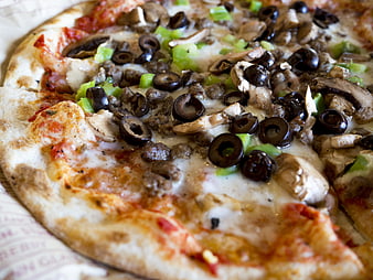 Close-up of rustic pizza with olives, mushrooms, and sausage